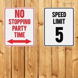K&ouml;nnte beinhalten: Zwei wei&szlig;e Schilder mit schwarzem Text und roten Akzenten. Das linke Schild zeigt "No Stopping Party Time" mit roten Pfeilen, die in entgegengesetzte Richtungen zeigen. Das rechte Schild zeigt "Speed Limit 5".