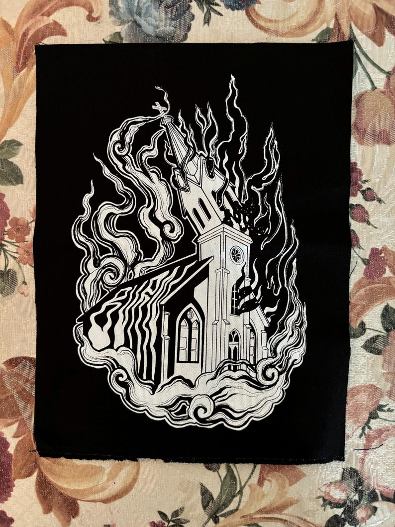 May include: Black and white embroidered patch of a church engulfed in flames. The church has a steeple and a clock tower. The flames are stylized and look like smoke.