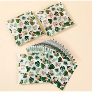 May include: A stack of clear plastic bags with a tropical leaf and flower print. The bags are perfect for packaging small gifts or treats.