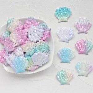 May include: A bowl filled with iridescent glitter seashells in shades of pink, blue, and green.  There are also several individual seashells scattered around the bowl.