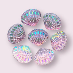 May include: Eight iridescent seashell-shaped buttons with a pink and purple iridescent finish.