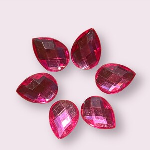 May include: Six pink teardrop-shaped rhinestones with a faceted design.