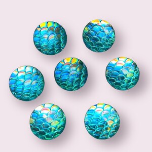 May include: Seven iridescent blue and green round buttons with a mermaid scale pattern.