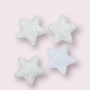 May include: Four white sparkly star-shaped embellishments.