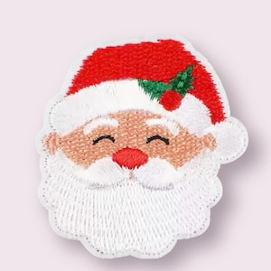 May include: Embroidered patch featuring Santa Claus's face. The patch has a red hat with white trim, a white beard, and a rosy face. The design includes a red nose, smiling eyes, and a sprig of holly. The patch is likely for clothing or accessories.