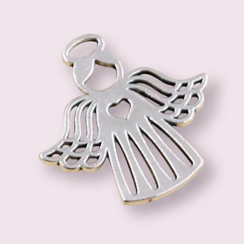 Puede incluir: Encanto de &aacute;ngel de plata con un coraz&oacute;n recortado. El &aacute;ngel tiene alas y un halo.