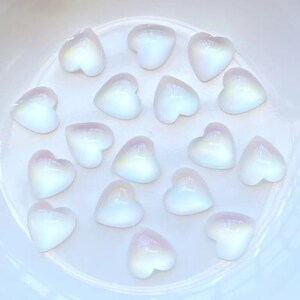 May include: A collection of 16 iridescent white heart-shaped cabochons, perfect for jewelry making or crafting.