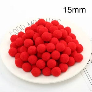 May include: A white plate filled with red pom poms, each measuring 15mm in diameter. The pom poms are soft and fluffy, perfect for crafting projects.
