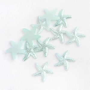 May include: A group of ten light blue, iridescent starfish with a pearlescent finish. The starfish are scattered on a white background.