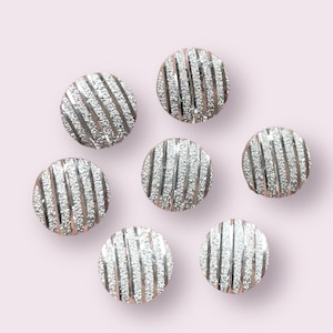 May include: Six silver-colored buttons with a textured, striped design. The buttons are round and have a shiny finish.