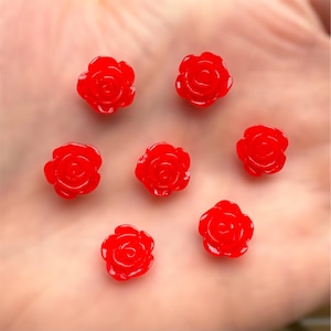 May include: Seven small, vibrant red rose-shaped beads. Each bead has detailed petals and a glossy finish. These decorative beads are ideal for jewellery making or craft projects.