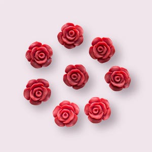 May include: Eight red rose-shaped resin embellishments, ideal for crafting projects.