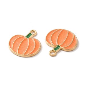 May include: Two gold-coloured pumpkin charms with a green stem and orange glitter finish.