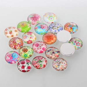 May include: Assortment of 16 round glass cabochons with floral patterns in various colours, including pink, blue, green, red, and yellow.