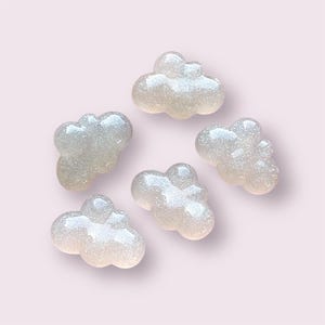 May include: Six white cloud-shaped resin embellishments with a glittery finish.