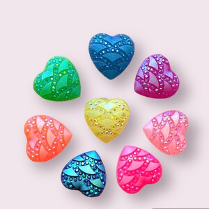 May include: Eight heart-shaped resin buttons in various colors, including blue, green, yellow, pink, and orange. Each button has a textured, iridescent finish.