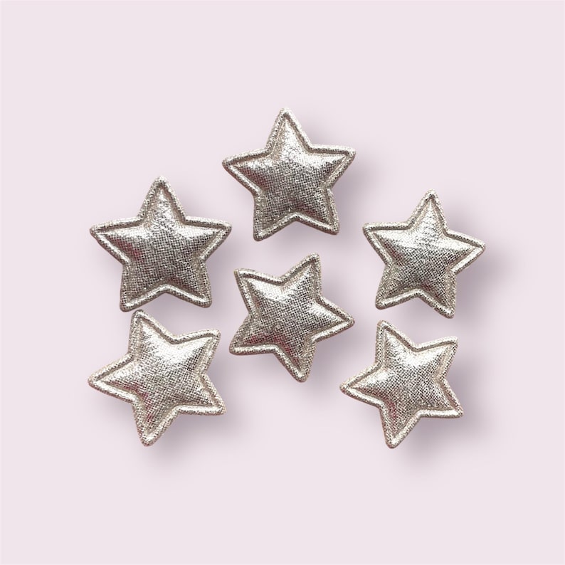 Pode incluir: Seis patches de tecido em forma de estrela com glitter prateado. As estrelas medem aproximadamente 5 cm de di&acirc;metro.