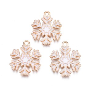 May include: Three gold-tone snowflake charms with white enamel. Each snowflake has a smaller star in the center.