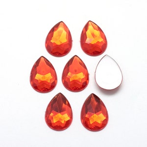 May include: Seven orange teardrop-shaped rhinestones and one clear teardrop-shaped rhinestone.