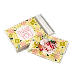 May include: A stack of yellow thank you cards with a floral pattern and pink lettering. The cards are packaged in a clear plastic bag with a smaller bag containing colourful confetti.