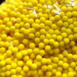 May include: A close-up image of a large quantity of bright yellow pom poms. The pom poms are soft and fluffy, and they are all the same size.