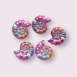 May include: Five iridescent purple seashell shaped buttons with a rainbow swirl design.