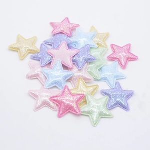 May include: A pile of pastel-colored, glittery, felt star shapes. The stars are in various shades of pink, blue, yellow, and green.