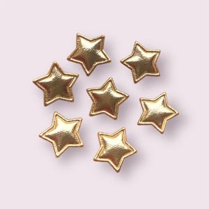 May include: Eight gold star-shaped embellishments with a textured surface.