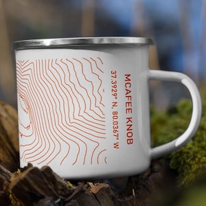 May include: White enamel camping mug with a topographic map design and the text "MCAFEE KNOB 37.3929° N, 80.0367° W" printed on the side.