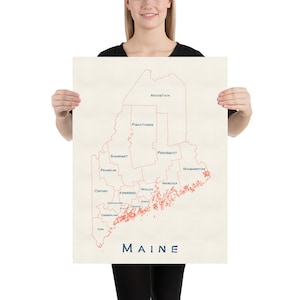May include: A map of Maine with the state's counties outlined in red and labeled in blue. The state's name is written in large blue letters at the bottom of the map.