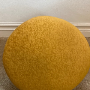 May include: A round, yellow, textured ottoman.
