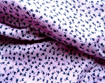 May include: Pink fabric with a black floral pattern. The fabric is textured and has a slight sheen.