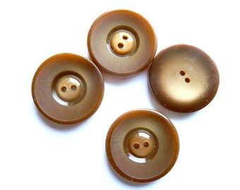 May include: Four brown plastic buttons with two holes each. The buttons have a slightly raised center and a glossy finish.