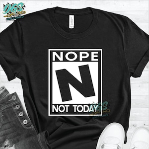 以下が含まれることがあります： 黒いTシャツに、白い正方形のグラフィックがプリントされています。グラフィックには、「NOPE」という文字がすべて大文字で書かれており、その下に黒い正方形の中に白い大きな「N」が書かれていて、「NOT TODAY」という文字が書かれています。