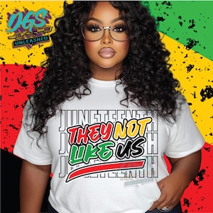 May include: White t-shirt with the text "Juneteenth They Not Like Us" in red, green, and black. The shirt is worn by a person with curly black hair and glasses. The background features the colours of the Pan-African flag.