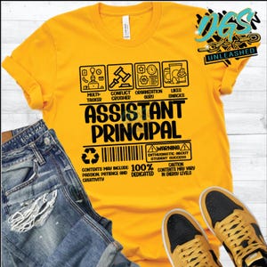 May include: Yellow t-shirt with a black graphic design that says "Assistant Principal". The graphic is a warning label with a list of qualities and skills, including "Multi-Tasker", "Conflict Crusher", "Organization Guru", "Likes Snacks", "100% Dedicated", and "Contents May Include Passion, Patience and Creativity".