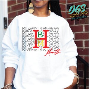 May include: White sweatshirt with the text "Black History Month" repeated multiple times with the letters "H", "B", and "M" in red, green, and yellow.