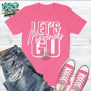 May include: Pink t-shirt with white text that says "Let's Mavericks Go".