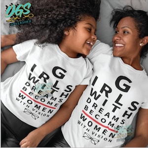 May include: Two white t-shirts with the text "Girls with dreams become women with vision" printed on them. The text is written in a way that makes it look like an eye chart.