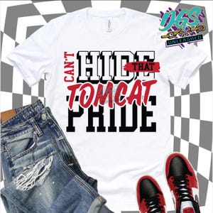 May include: White t-shirt with the text "CAN'T HIDE THAT TOMCAT PRIDE" in black and red. The shirt is paired with blue denim jeans and red and black sneakers. The image is set against a checkered background.
