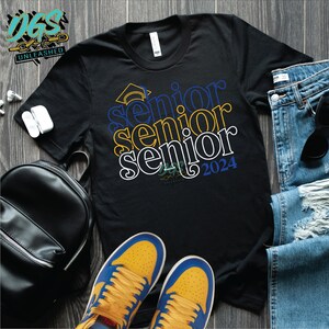 Puede incluir: Camiseta negra con las palabras "Senior" apiladas una encima de la otra en letras blancas, azules y amarillas. La palabra superior tiene un gorro de graduación encima. La palabra inferior tiene el año "2024" a su lado.