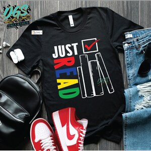 May include: Black t-shirt with the text "JUST READ" in colorful letters and a stack of books with a checkmark next to it.