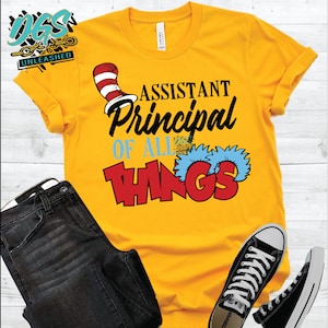 May include: Yellow t-shirt with a red and white cat hat and the text "Assistant Principal of All Things" in black and red lettering.