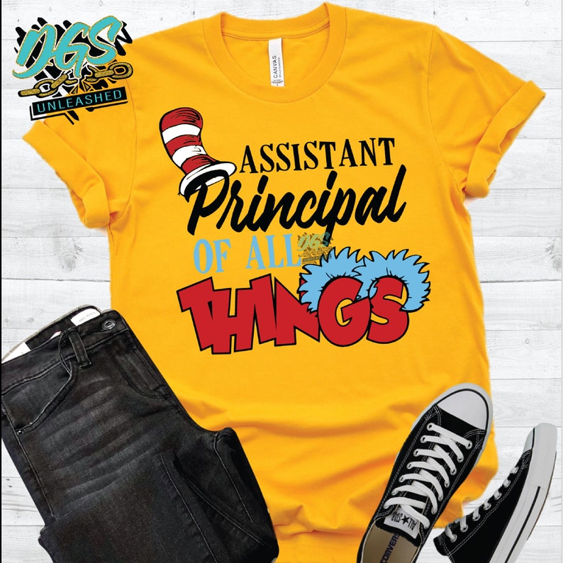 May include: Yellow t-shirt with a red and white cat hat and the text "Assistant Principal of All Things" in black and red lettering.