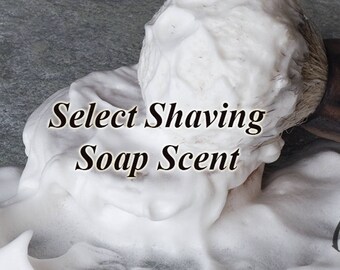 May include: Close-up of a shaving brush lathering shaving soap. The soap is white and fluffy, and the text "Select Shaving Soap Scent" is visible in the center of the image.
