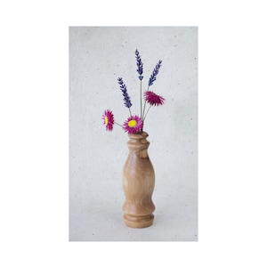 May include: A wooden vase with a unique shape, holding a bouquet of purple lavender and pink flowers with yellow centers.