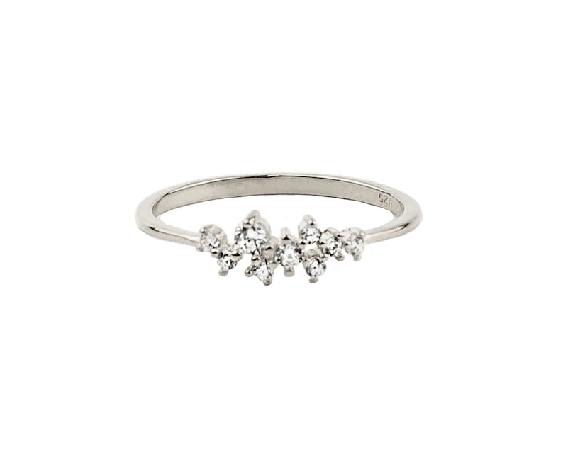 May include: A silver ring with a cluster of small, clear stones set in a delicate band.