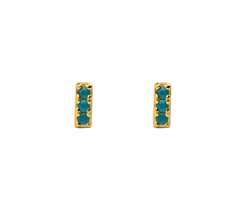 May include: A pair of gold stud earrings with a vertical bar design. Each bar is set with three turquoise gemstones.