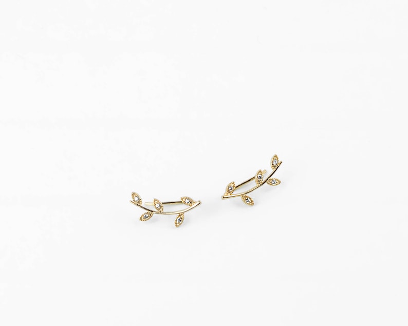 May include: A pair of gold leaf ear climbers with small clear stones set in each leaf.