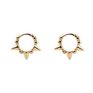 Puede incluir: Un par de pendientes de aro de oro con un diseño circular y pequeñas púas alrededor del borde.
